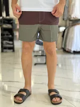 Short de baño con diseño bicolor en tonos gris y rosado, con costuras decorativas visibles en contraste y pequeño aplique circular en el lateral.