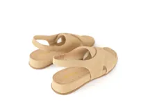 Sandalias de gamuza color avena, con diseño de tiras cruzadas en el empeine, talón destalonado con elástico interno para mayor sujeción y suela plana con leve plataforma.