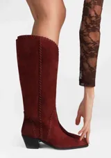 Bota alta de cuero color malbec, con taco bajo y detalles de costura en contraste a lo largo de la caña.