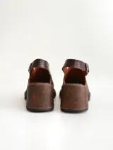 Zapato tipo zueco de cuero color chocolate con efecto desgastado, plataforma y taco cuadrado. Presenta una tira trasera ajustable con hebilla metálica.