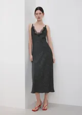 Vestido midi de estilo lencero color negro con estampado de lunares blancos, escote en V con detalle de encaje negro, tirantes finos y diseño entallado.