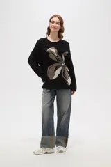 Sweater de punto jacquard con diseño floral abstracto en tonos tierra sobre fondo negro, de corte holgado, cuello redondo y manga larga.