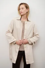 Spolverino largo de jean color azul, con cuello camisero, botones frontales y costuras decorativas en blanco.