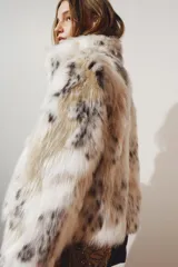Abrigo corto ZW Collection de cuello solapa y manga larga, con detalle de aplicación efecto pelo sintético y estampado animal print abstracto en tonos blancos, beige y negros. Cuenta con bolsillos delanteros, bajo recto y cierre frontal con botones ocultos.