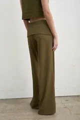 Pantalón palazzo negro de tiro alto con cintura ancha plegable, confeccionado en tela de punto fruncida y corte holgado.