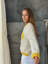 Sweater tejido a mano en Uruguay, 100% lana merino color crudo, con cuello, puños y ruedo en amarillo. Presenta un corazón amarillo en el frente.