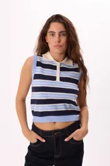 Top tejido sin mangas con diseño a rayas horizontales en tonos azul marino, celeste y crema. Presenta cuello tipo polo con tapeta de botones frontal y terminaciones acanaladas en el ruedo y sisas.