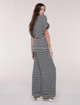 Conjunto de dos piezas de calce fluido y relajado con estampado geométrico en blanco y negro. Incluye una chaqueta con escote en V, solapa, diseño cruzado con lazo y bolsillos con solapa en el pecho, y un pantalón de tiro alto y corte wide leg.