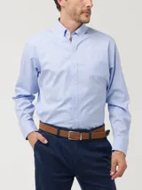 Camisa de manga larga en tejido oxford color celeste claro, con cuello abotonado, bolsillo en el pecho y cierre frontal con botones.