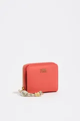 Billetera Bimba y Lola de color coral, de diseño compacto y cierre de cremallera perimetral con tirador de cuerda decorativa. Incluye el logotipo de la marca impreso en letras doradas en el frente.
