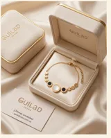 Pulsera de acero con baño de oro, compuesta por una cadena de eslabones y tres dijes circulares centrales, uno de nácar blanco y dos de ónix negro.