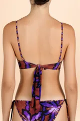 Top de bikini con diseño tipo corsetero, escote en V y sistema de amarre halter. Presenta un estampado botánico con hojas en tonos violeta y detalles en color cobre.
