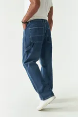 Jean estilo carpenter de corte relajado, recto y amplio, con diseño de cinco bolsillos y costuras reforzadas características del modelo. Presenta un acabado lavado en tono gris oscuro.
