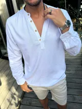 Camisola de manga larga en tejido de lino color blanco, con cuello mao y cierre frontal parcial con botones de madera.