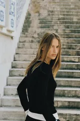 Camiseta de manga larga color gris melange, con cuello redondo y bajo recto. Presenta un detalle de tejido efecto doble a contraste en el cuello, puños y dobladillo inferior en color blanco.