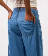 Pantalón de jean estilo aladín con tiro medio, cintura con pasadores, cierre frontal con botón y bolsillos funcionales. Presenta un calce amplio con diseño tipo globo y terminación ajustada en los puños.