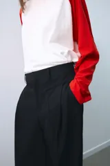 Pantalón de tiro medio color beige, de corte ancho y recto, con pinzas frontales y trabillas en la cintura.