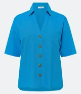 Camisa de manga corta confeccionada en mezcla de viscosa y lino color turquesa. Presenta cuello camisero con escote en V, bolsillos frontales de parche y cierre frontal con botones geométricos de efecto carey.