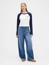 Remera de manga larga estilo raglán con cuerpo en color crema y mangas en color verde oscuro. Presenta un pequeño logo estampado en el pecho.