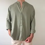 Camisa de lino color verde militar, de corte regular, con cuello mao y mangas largas con puños vueltos.