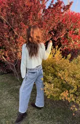 Pantalón de jean de corte wide leg, con lavado ácido y costuras decorativas bordadas a mano en color crudo a lo largo de los laterales y los bolsillos traseros.