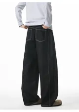 Pantalón de jean negro de corte muy ancho (baggy), con costuras exteriores en hilo blanco contrastante.