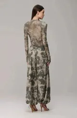 Pantalón de corte holgado con estampado camuflado en tonos verdes y beige. Presenta cintura elástica con cordón ajustable y puños inferiores también ajustables con cordón, permitiendo modificar su silueta.