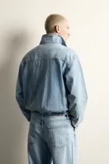 Cazadora de denim de algodón con efecto lavado, corte cropped, cuello solapa, cierre frontal con cremallera de doble dirección, manga larga con puños abotonados y bolsillos laterales.