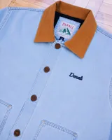 Campera de estilo workwear confeccionada en canvas resistente color azul claro, con interior forrado en corderito sherpa. Presenta cuello de pana en color tostado, cierre frontal con botones metálicos, dos bolsillos frontales amplios y bordado de la marca en el pecho.