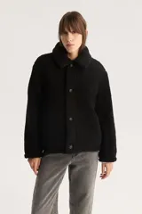 Campera negra de sherpa con cuello camisero, cierre con botones a presión y calce estándar.