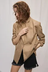 Blazer de silueta amplia y largo por debajo de la cadera, color café, confeccionado en tela suave y liviana. Presenta cuello con solapas, cierre cruzado con botones y bolsillos laterales con tapa.