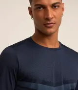 Remera deportiva de manga larga con cuello redondo, confeccionada en tejido de malla de poliéster. Presenta un diseño con estampado geométrico tipo delta punteado en el pecho.