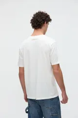 Remera blanca de manga corta con estampa frontal de una ilustración arquitectónica abstracta y calce clásico.
