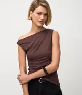 Blusa de microfibra color marrón, con diseño de hombro único, detalle torcido en el tirante y fruncidos laterales. Presenta un corte ajustado y dobladillo asimétrico.