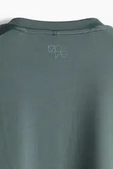 Remera deportiva verde con cuello redondo, mangas cortas, bajo recto con aberturas laterales y espalda algo más larga.