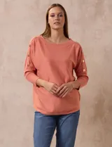 Buzo tejido color salmón de hilado fino, marca Cable & Gauge. Escote redondo con calados. Manga ¾, modelo dolman con aplique de botones dorados.