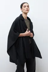 Capa negra con solapa y cuello tejido, de corte amplio y sin mangas.