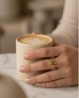 Anillo de acero con baño de oro, diseño calado con formas geométricas de rombos y detalles de esferas pequeñas.