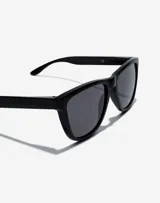 Gafas de sol unisex Hawkers modelo One Raw, de acetato color negro con lentes grises.