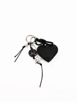 Llavero con argolla metálica, compuesto por un dije de corazón negro acolchado, un dije de estrella plateada, una cuenta con estampado animal print y cordones negros.