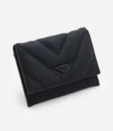 Billetera pequeña tipo sobre marca Satinato, confeccionada en poliuretano con acabado acolchado y textura granulada. Presenta un diseño geométrico con costuras en forma de V y un aplique metálico triangular con el logo de la marca en el frente. Cuenta con cierre a presión.