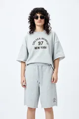 Bermuda marrón de algodón y poliéster, corte relajado, tiro medio, cordón ajustable en la cintura y estampado con inspiración college.