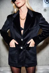 Blazer negro de terciopelo con solapa en V, botones plateados y bolsillos laterales.