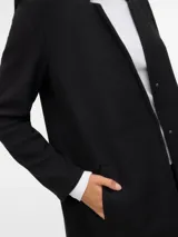 Campera larga de tejido interlock, color negro, con cuello mao, cierre frontal a presión y bolsillos laterales funcionales.