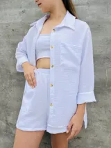 Conjunto blanco de camisa de manga larga con botones y shorts con bolsillos.