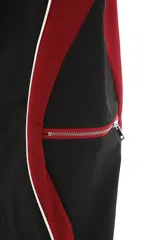 Pantalón deportivo de calce amplio y oversize, color negro con paneles laterales en rojo y vivos blancos que recorren el corte. Posee bolsillo lateral con cierre y cintura regulable.