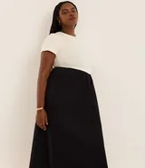 Vestido midi bicolor, con parte superior color crema y falda negra, confeccionado en tejido de punto rib de algodón. Tiene escote redondo y mangas cortas.