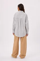 Camisa de manga larga con diseño de rayas verticales en tonos azul, blanco y beige, cuello camisero y cierre frontal de botones.