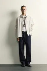 Camisa relaxed fit de algodón con estructura, cuello solapa, manga larga con puño abotonado, bolsillo de parche en el pecho y cierre frontal con botones. Presenta diseño de rayas finas.