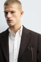 Blazer de corte regular confeccionado en tejido con lana, color marrón oscuro. Presenta cuello con solapas de muesca, cierre frontal de un botón, bolsillos con solapa en la cadera y bolsillo de vivo en el pecho.